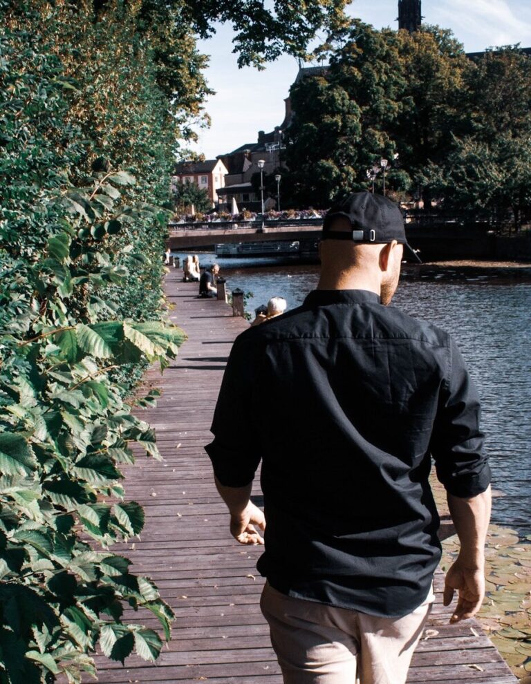 man in black jacket and brown shorts standing on wooden dock during daytime