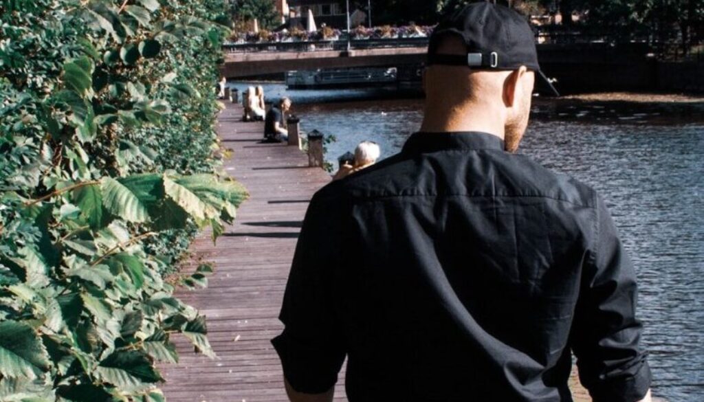 man in black jacket and brown shorts standing on wooden dock during daytime