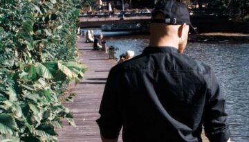 man in black jacket and brown shorts standing on wooden dock during daytime
