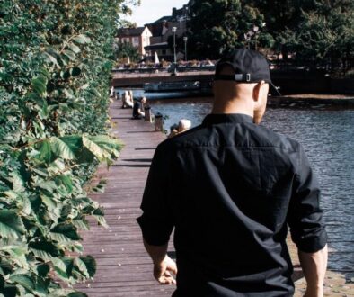 man in black jacket and brown shorts standing on wooden dock during daytime