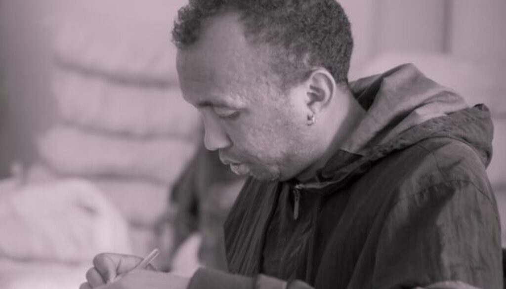 a man sitting at a desk writing on a piece of paper