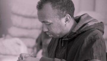 a man sitting at a desk writing on a piece of paper