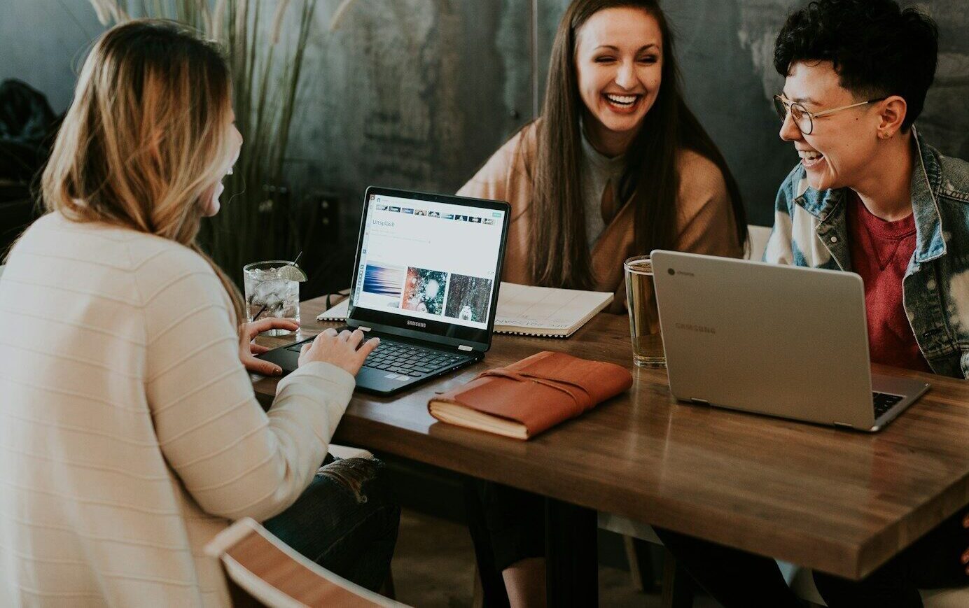 Drie cursisten zitten aan tafel te lachen